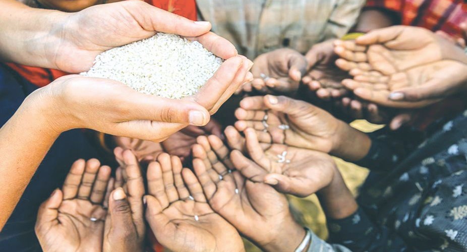Volunteer caucasian woman giving rice to hungry Indian children. Poor Indian children keeping their hands up and asking for support. Many Indian children suffer from poverty - more than 50% of India's total population  lives below the poverty line, and more than 40% of this population are children.
